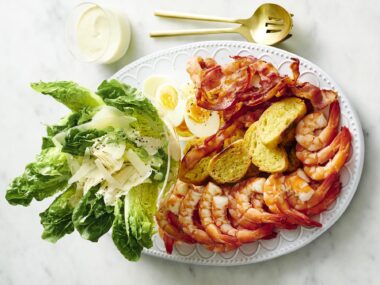 prawn and salad greens on a plate to form a prawn caesar salad