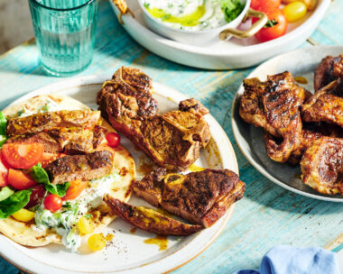 A pita wrap with lettuce, tomato and tzatziki and lamb chops on the side.