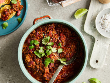 Slow cooker chilli con carne served with with corn chips and lime wedges