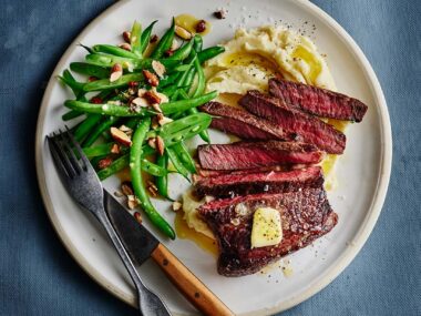 Chargrilled rump steak with Dijon maple butter, green beans and mashed potato on a dinner plate